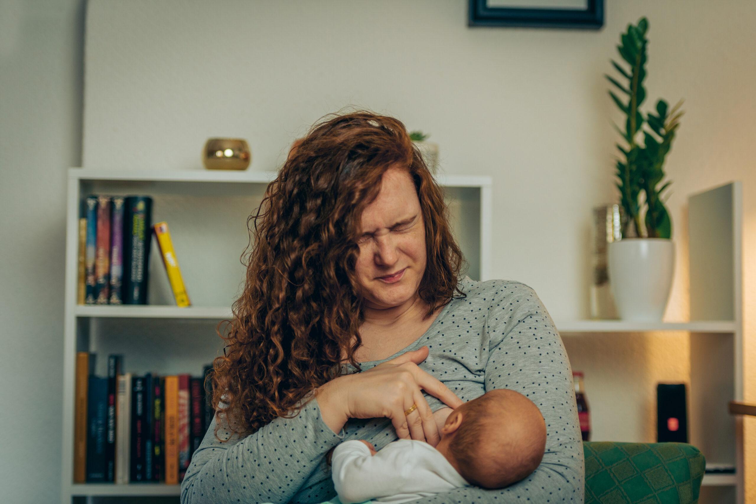 Newly mother breastfeeding her newborn baby boy while in pain